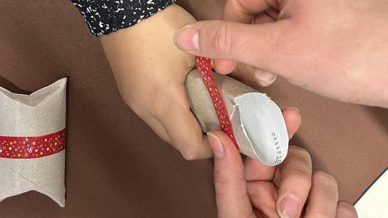 Es sind Hände zweier bastelnder Personen zu sehen.